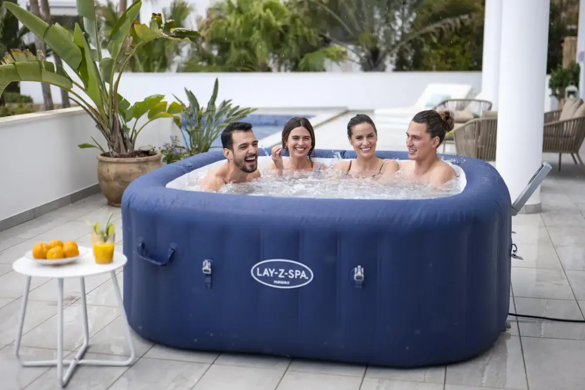 Cztery osoby śmieją się w dmuchanym jacuzzi Bestway Lay-Z-Spa Hawaii na tarasie.