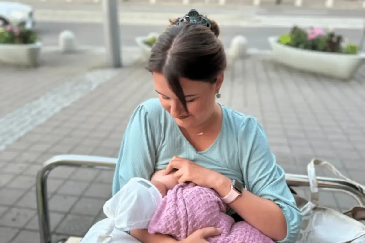 Mama karmi piersią dziecko na ławce w parku. Naturalne karmienie piersią w miejscu publicznym to piękny widok.