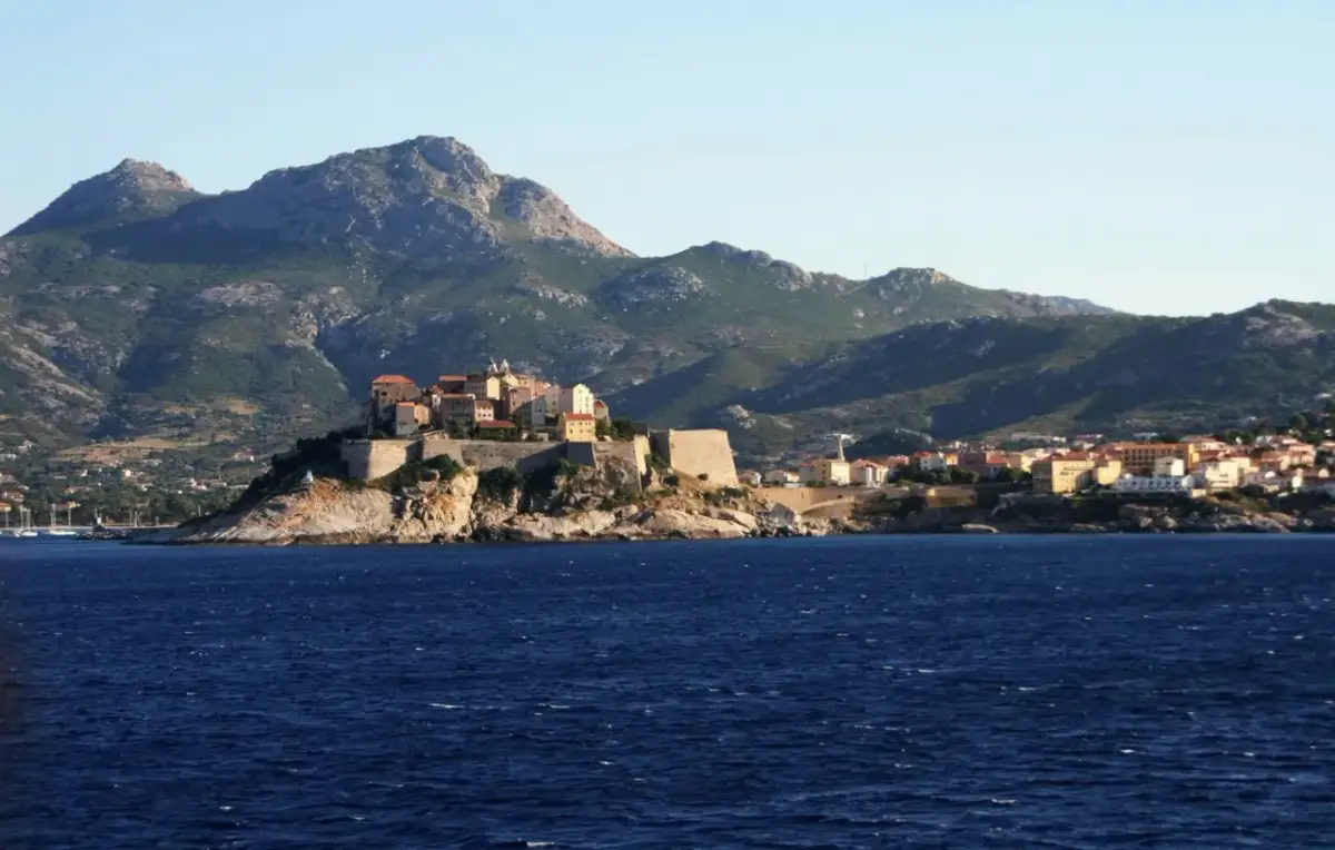 Widok na miasteczko na klifie z fortecą, w tle góry. Idealne miejsce na GR20 Korsyka.