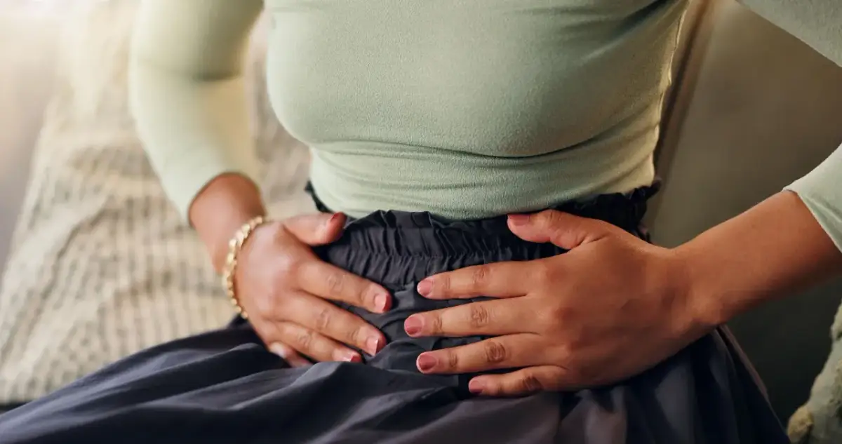 Kobieta trzymająca się za brzuch, odczuwająca ból.