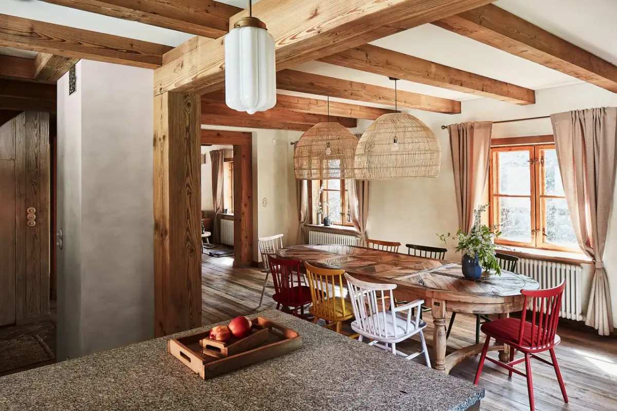 Drewniany dom z jadalnią, stołem, kolorowymi krzesłami i wiklinowymi lampami.
