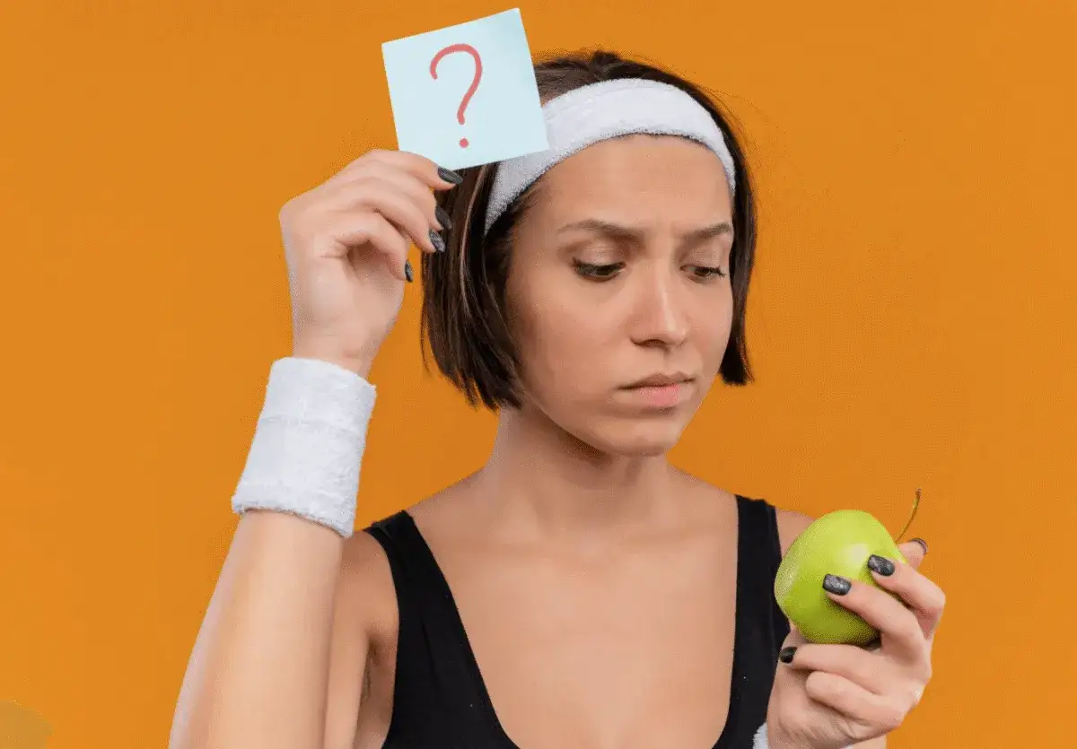 Zastanawiasz się, co jeść na pamięć i koncentrację? Młoda kobieta z opaską na głowie trzyma jabłko i kartkę z pytajnikiem.