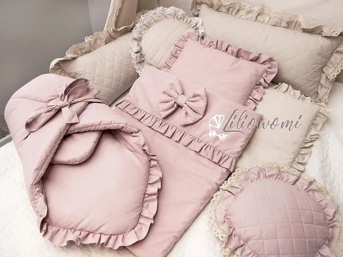 Różowa pościel do gondoli z falbankami i kokardą. W zestawie poduszka z haftem i śpiworek.