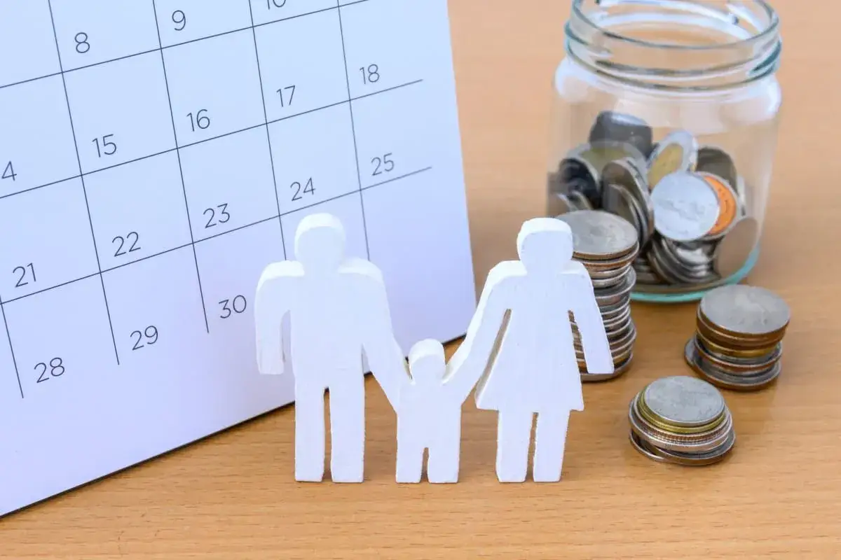 Figurki rodziny, kalendarz i słoik z monetami.