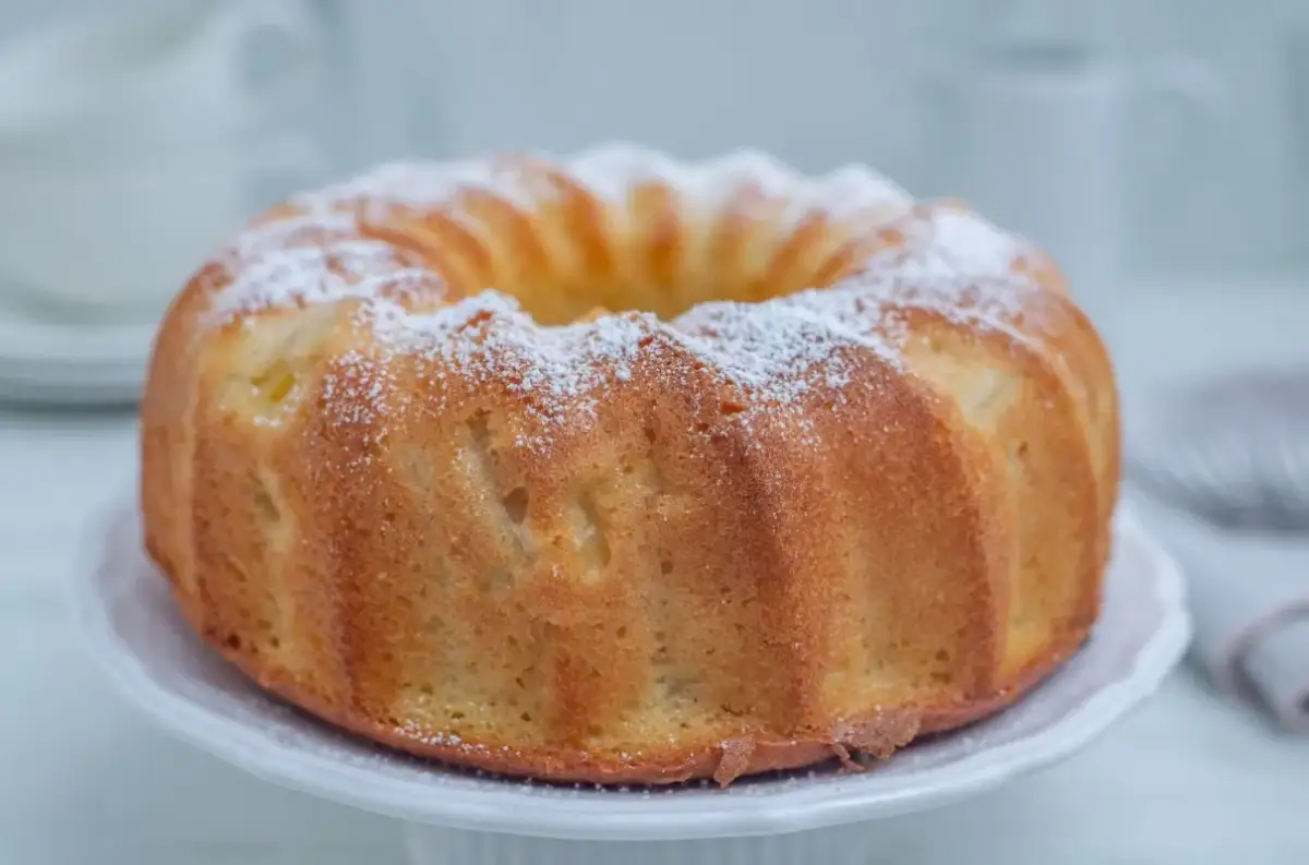 Puszysta babka na oleju, oprószona cukrem pudrem, prezentuje się apetycznie na białej paterze. Idealna na niedzielne popołudnie.
