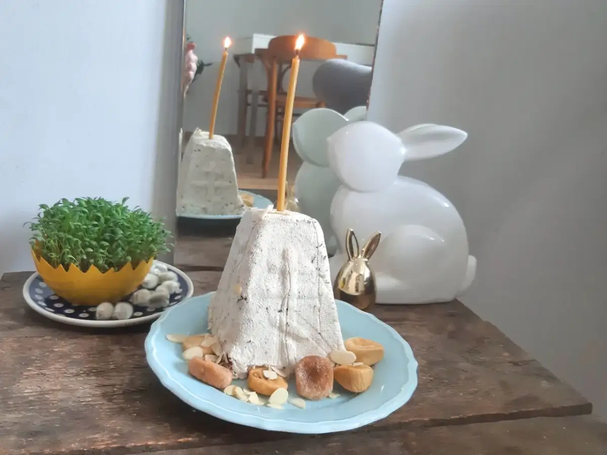 Nowoczesne potrawy wielkanocne: pyszna pascha z bakaliami, świeża zielenina i ozdobne zajączki.