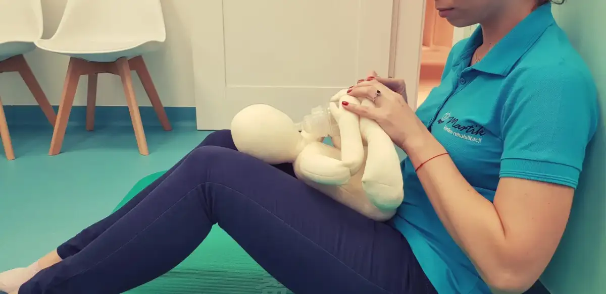 Terapeuta ćwiczy pozycję do karmienia butelką z pluszowym niemowlakiem.