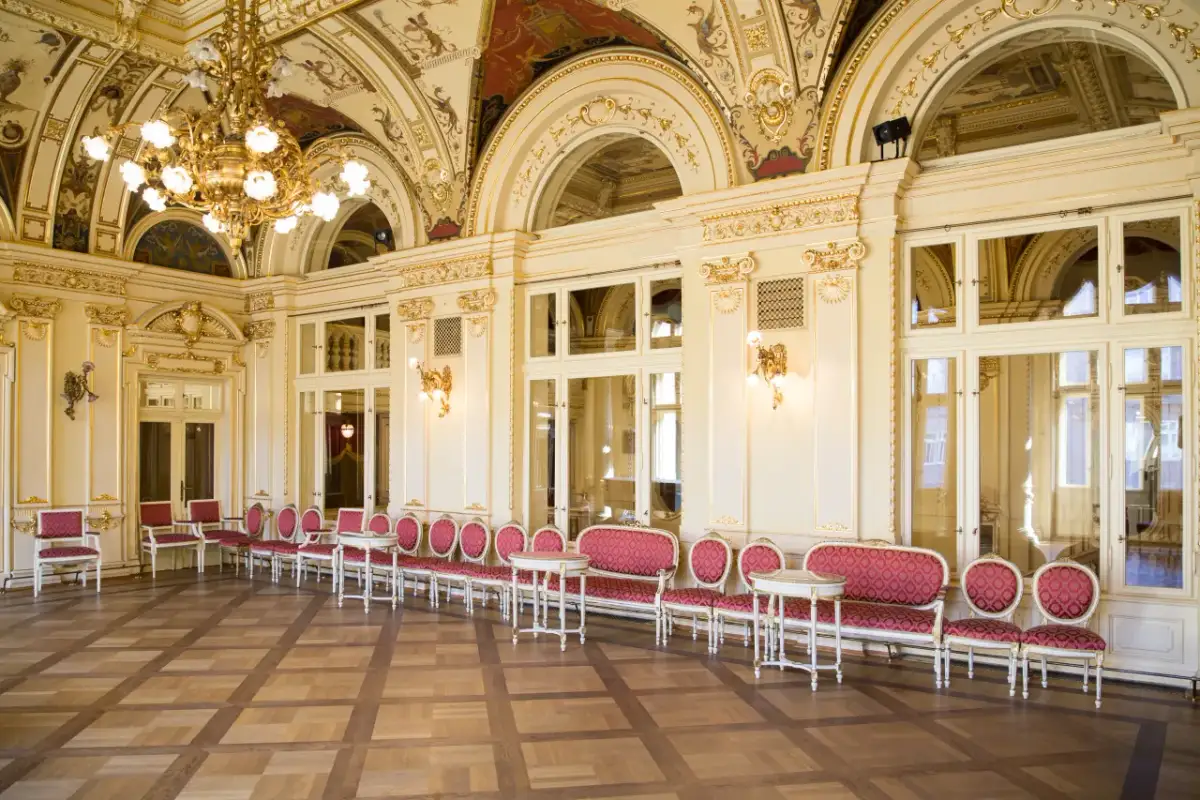 Eleganckie, złocone wnętrze z rzędami czerwonych foteli i stolików. To właśnie co to jest foyer w teatrze – miejsce spotkań przed spektaklem.