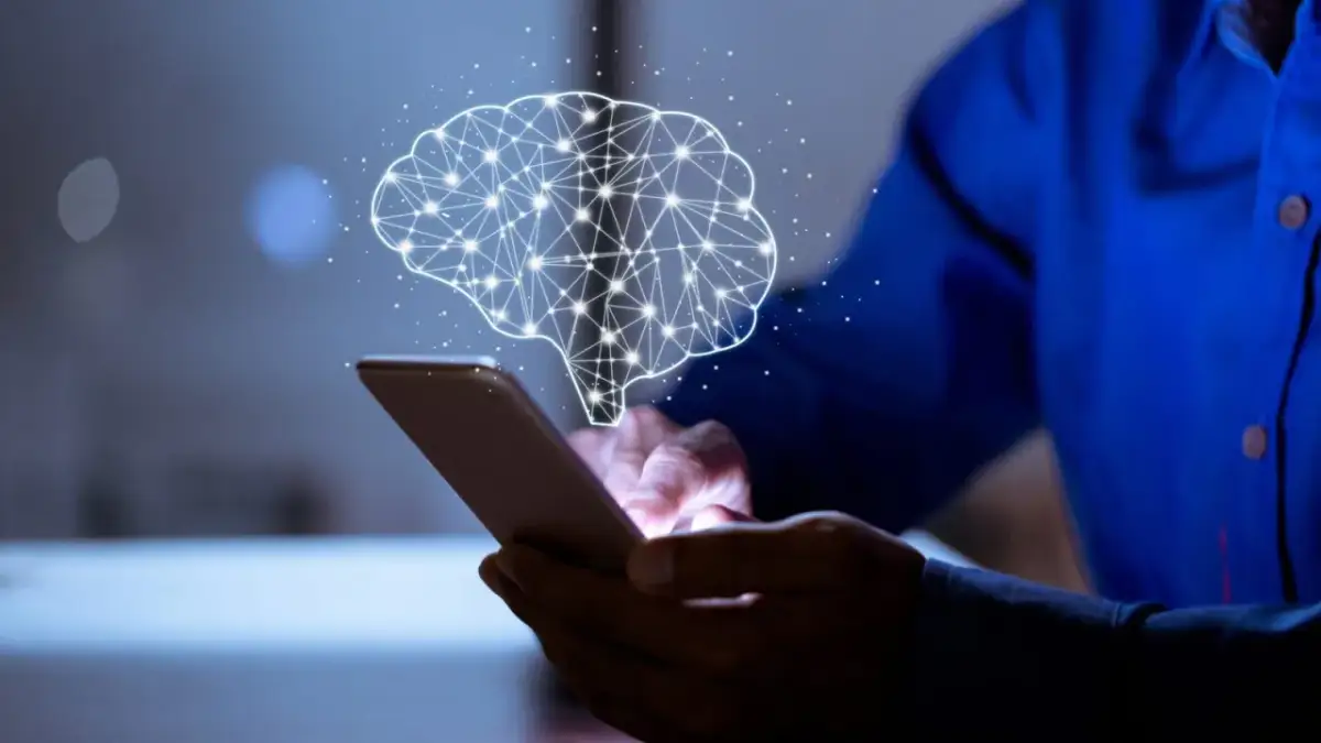 Dłoń trzyma smartfon, nad którym unosi się świetlisty mózg. Aplikacja pomaga zrozumieć, ile czasu się trzeźwieje.