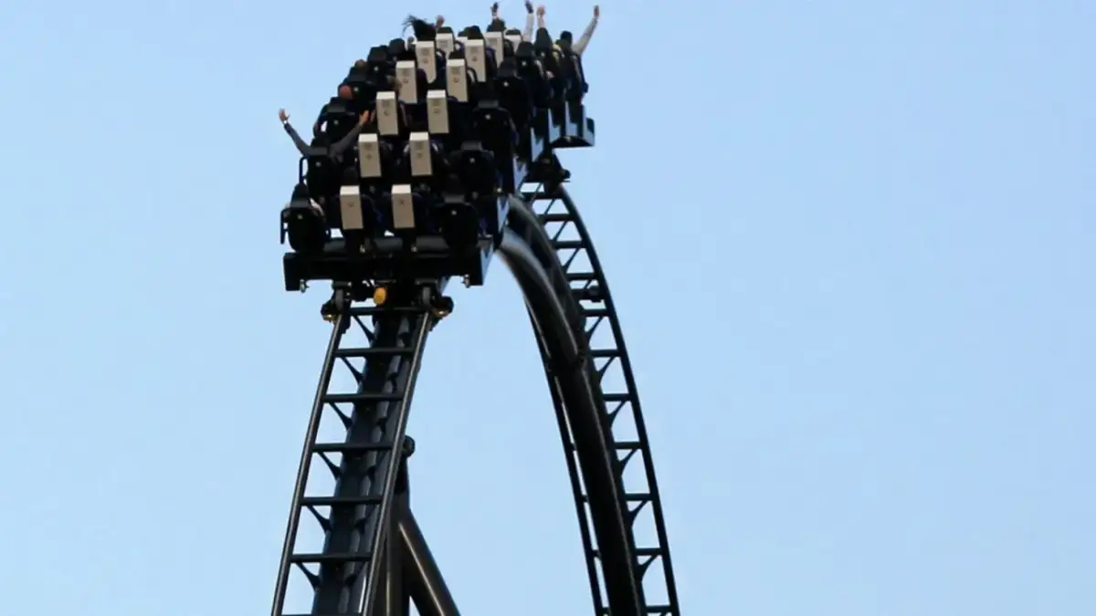 Kolejka górska Hyperion z pasażerami z rękami w górze na tle błękitnego nieba.