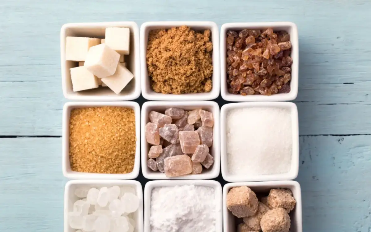 Neuf carrés blancs remplis de différents types de sucre : cubes blancs, cassonade, sucre candi, etc.