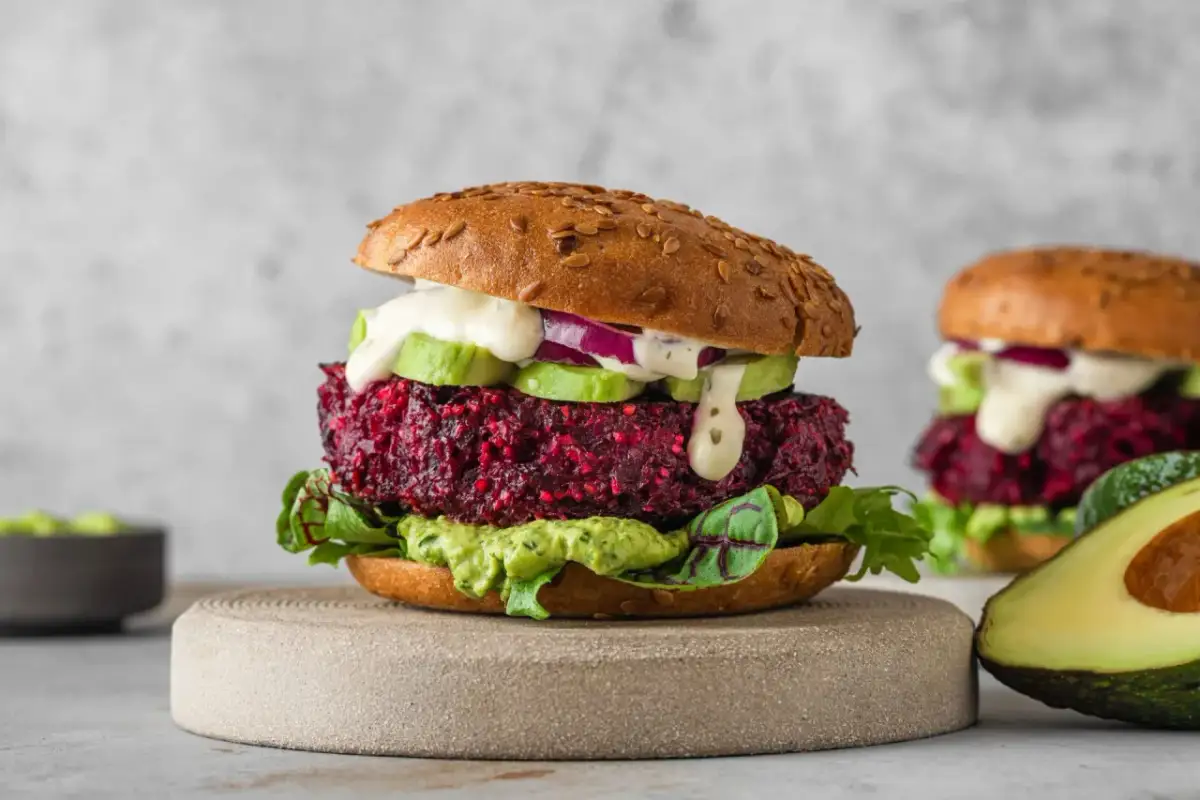 Pyszny burger z buraka z awokado, czerwoną cebulą i kremowym sosem. Idealna wegetariańska alternatywa.