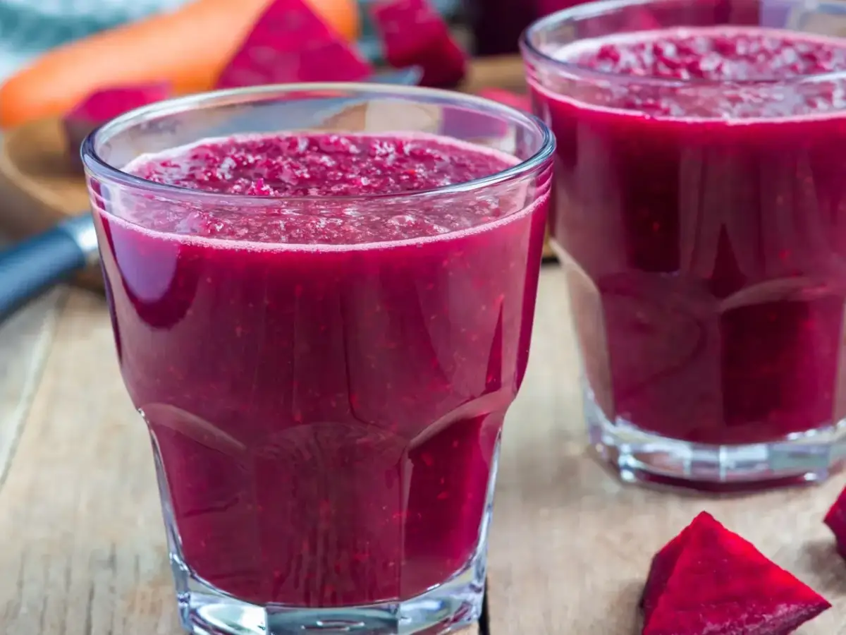 Intensywny, rubinowy koktajl z buraka na odchudzanie, orzeźwiający i pełen witamin. Obok leżą kawałki buraka i marchewki.