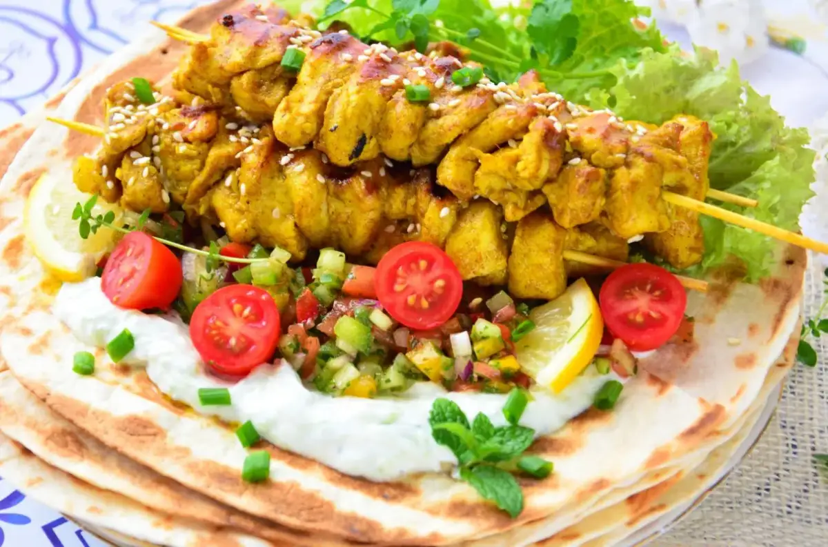 Pyszna shoarma z kurczaka na chlebku pita, z jogurtowym sosem, świeżymi warzywami i cytryną.