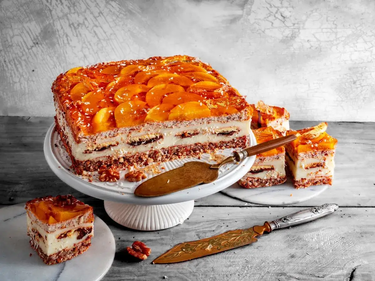 Pyszne ciasto kora dębu z brzoskwiniami i kremem, udekorowane wiórkami kokosowymi. Idealne na deser.