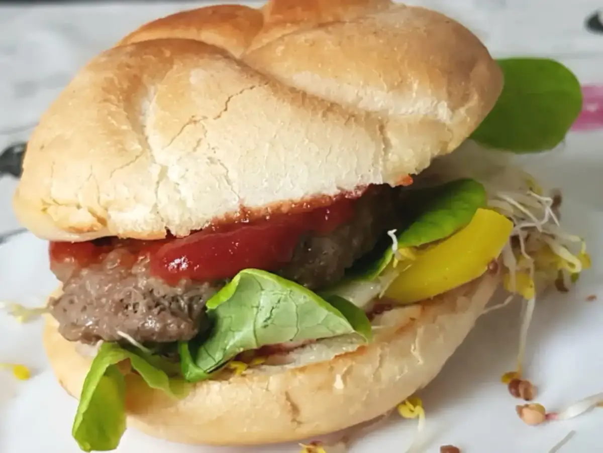 Pyszny burger z soczystym kotletem, sałatą, keczupem i żółtym serem. Idealny przykład, jak usmażyć burgera na patelni.