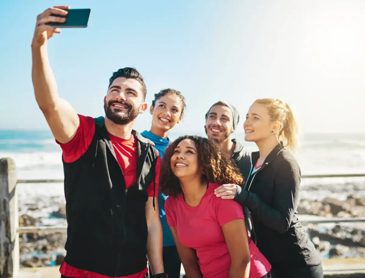 Grupa przyjaciół robi sobie selfie nad morzem. Ich uśmiechy to najlepsze cytaty o sobie, pełne radości i wspólnych chwil.