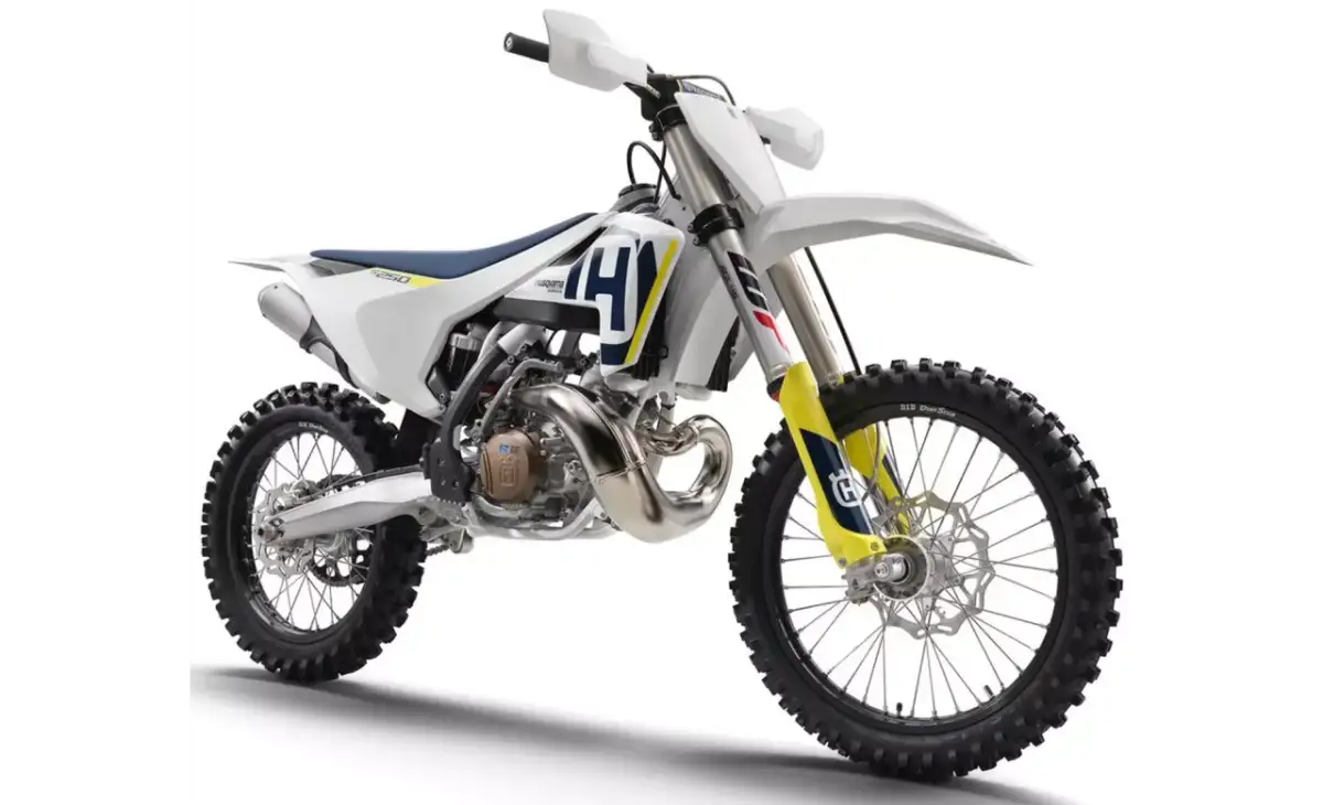 Nowy motocykl cross Husqvarna 250 gotowy na wyzwania toru. Biało-niebiesko-żółte malowanie, potężny silnik i terenowe opony.
