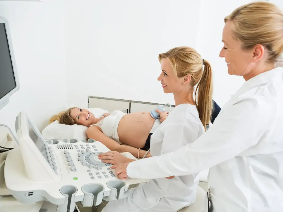 Ciężarna kobieta na USG. Czy do ginekologa trzeba mieć skierowanie od lekarza rodzinnego? Lekarka wykonuje badanie.