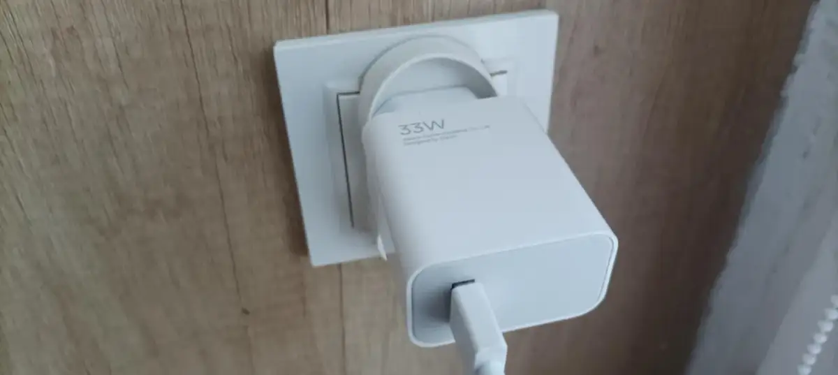 Biała ładowarka 33W Xiaomi podłączona do gniazdka. Czy podłączona ładowarka ciągnie prąd? Tak, nawet bez podłączonego urządzenia, pobiera minimalną moc.