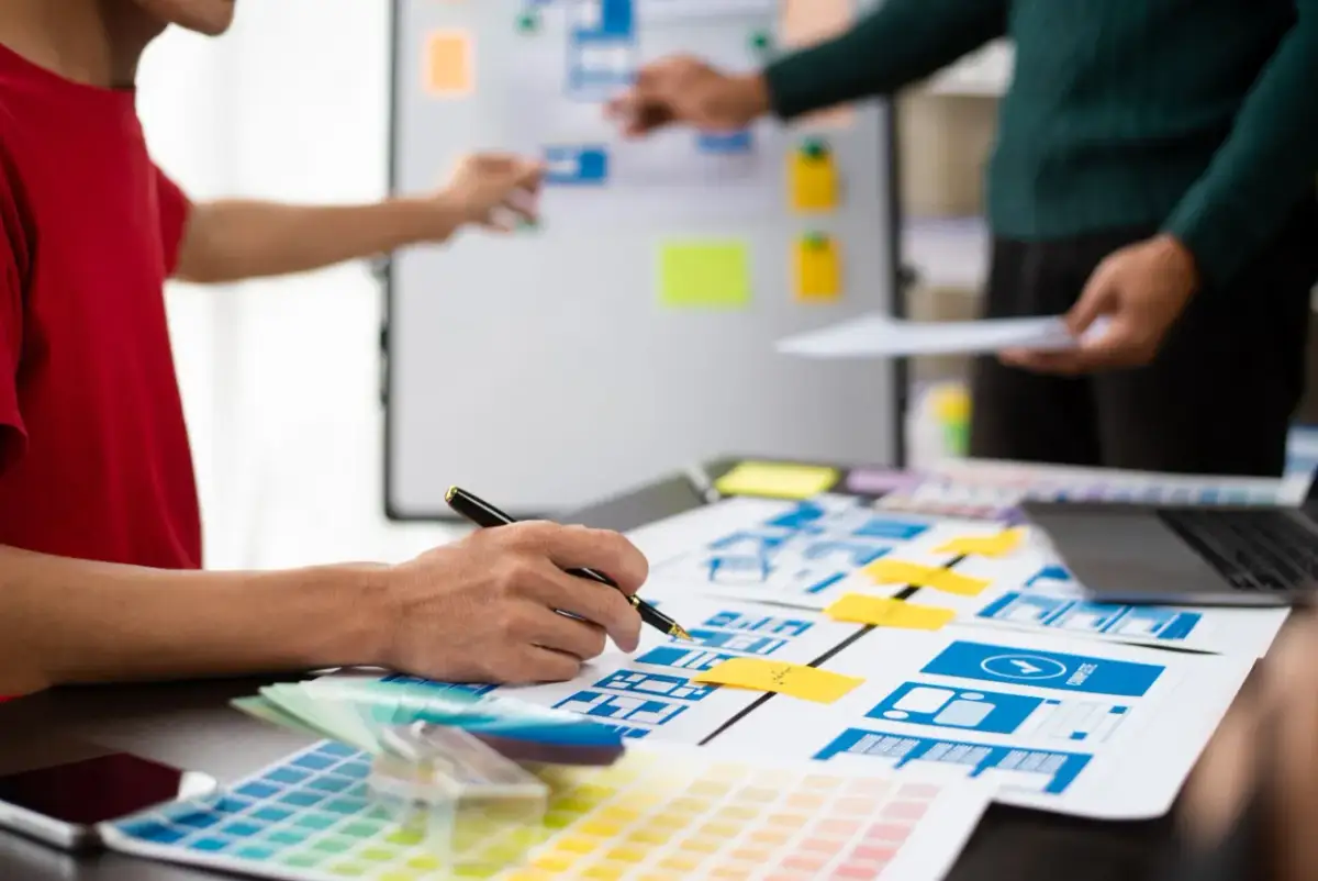 Zespół projektuje interfejsy użytkownika, analizując makiety i palety kolorów.