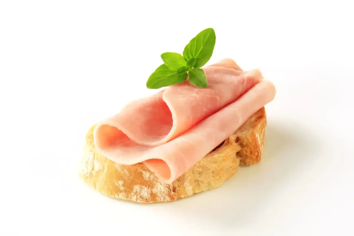 Kanapka z szynką i masłem, ozdobiona listkiem mięty. Zastanawiasz się, ile kalorii ma kanapka z szynką i masłem?