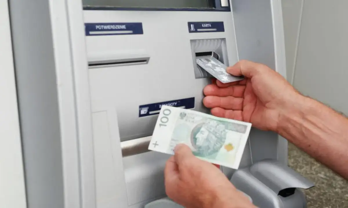 Wpłatomat przyjmuje banknoty, w tym 100 zł. Widać też wkładanie karty.