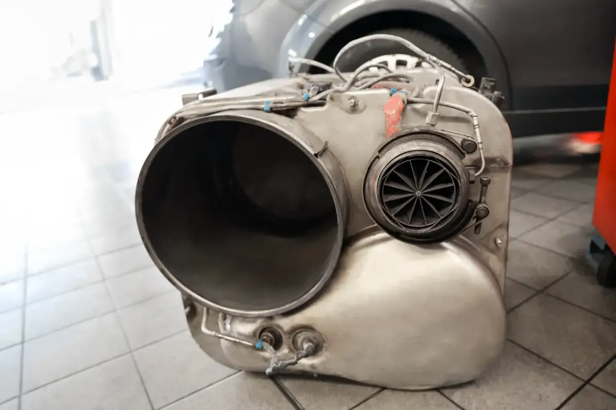 Metalowy element układu wydechowego, prawdopodobnie turbosprężarka lub katalizator, leży na podłodze. Brak DPF może skutkować mandatem.