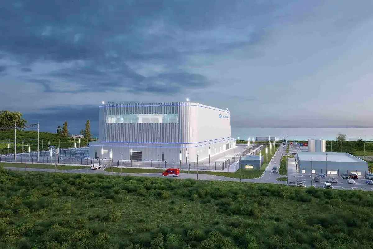 Wizualizacja nowoczesnej elektrowni atomowej Hitachi, która może powstać w Polsce. Obiekt zlokalizowany nad morzem, otoczony zielenią.