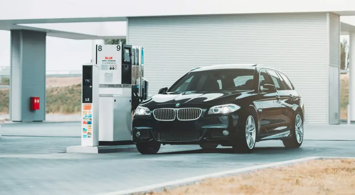 Czarne BMW na stacji paliw. Przykład, jak odliczyć 50% VAT od paliwa, może być związany z kosztami podróży służbowych.