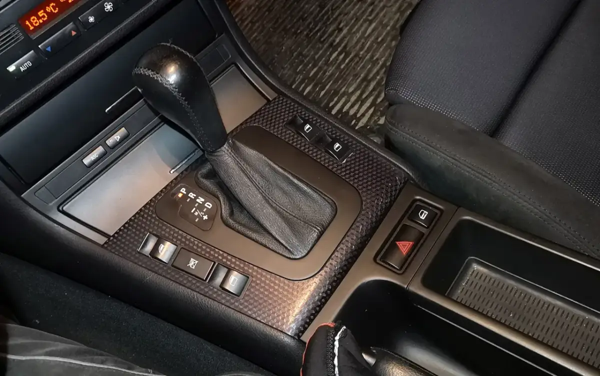 Wnętrze auta po malowaniu plastików. Widoczny lewarek skrzyni biegów, przyciski i panel z włókna węglowego.