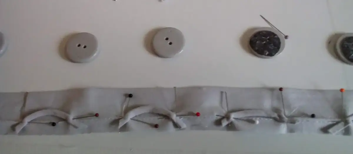 Przygotowanie pętelek do zapięcia swetra. Guziki i materiał z agrafkami czekają na zszycie.