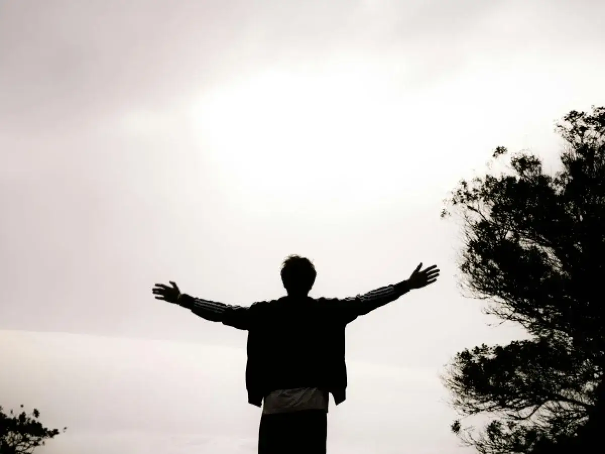 Sylwetka człowieka z rozłożonymi ramionami, jakby w geście powitania lub akceptacji. To przesłanie pana cogito interpretacja wolności.