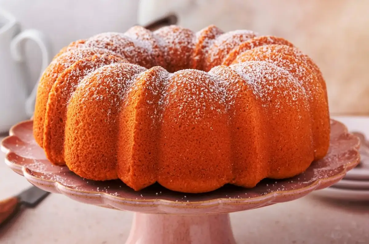 Złocista babka z kisielem, oprószona cukrem pudrem, prezentuje się apetycznie na różowej paterze.