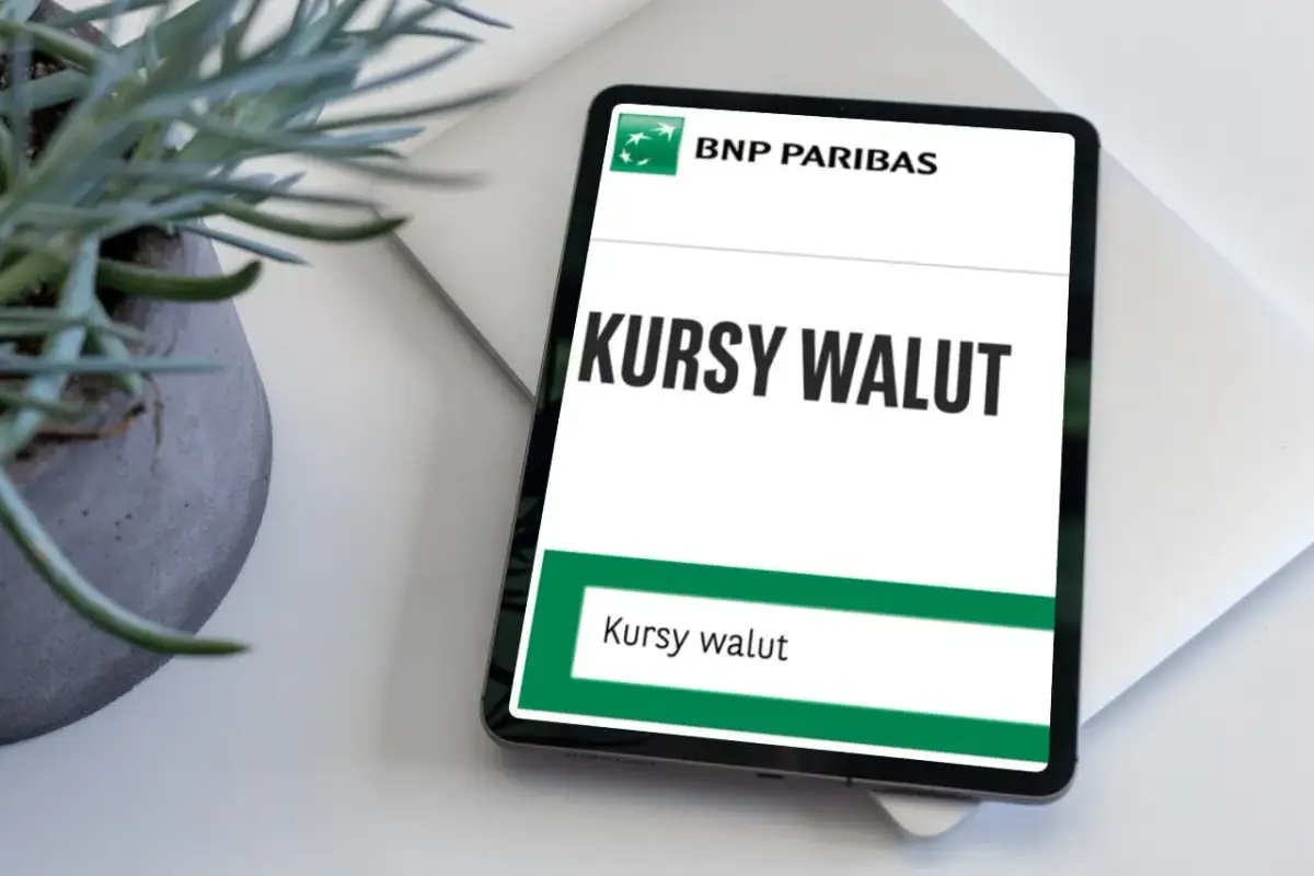 Tablet z aplikacją BNP Paribas wyświetla "Kursy walut". Obok stoi doniczka z rośliną.