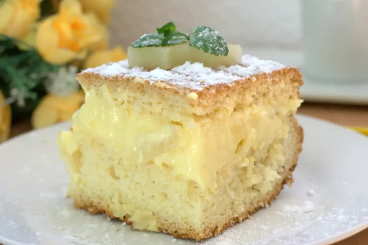 Puszyste ciasto z ananasem z puszki i budyniem, posypane cukrem pudrem i udekorowane miętą.