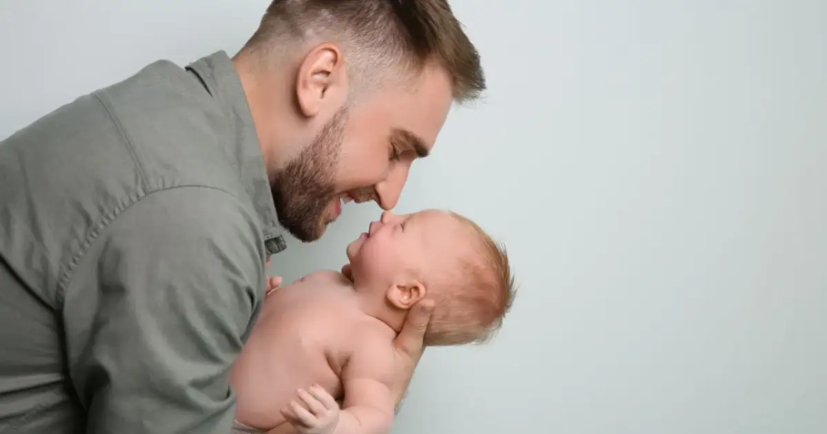 Ojciec pochyla się nad dzieckiem, dotykając noskami. Czy po kim dziecko dziedziczy inteligencję?