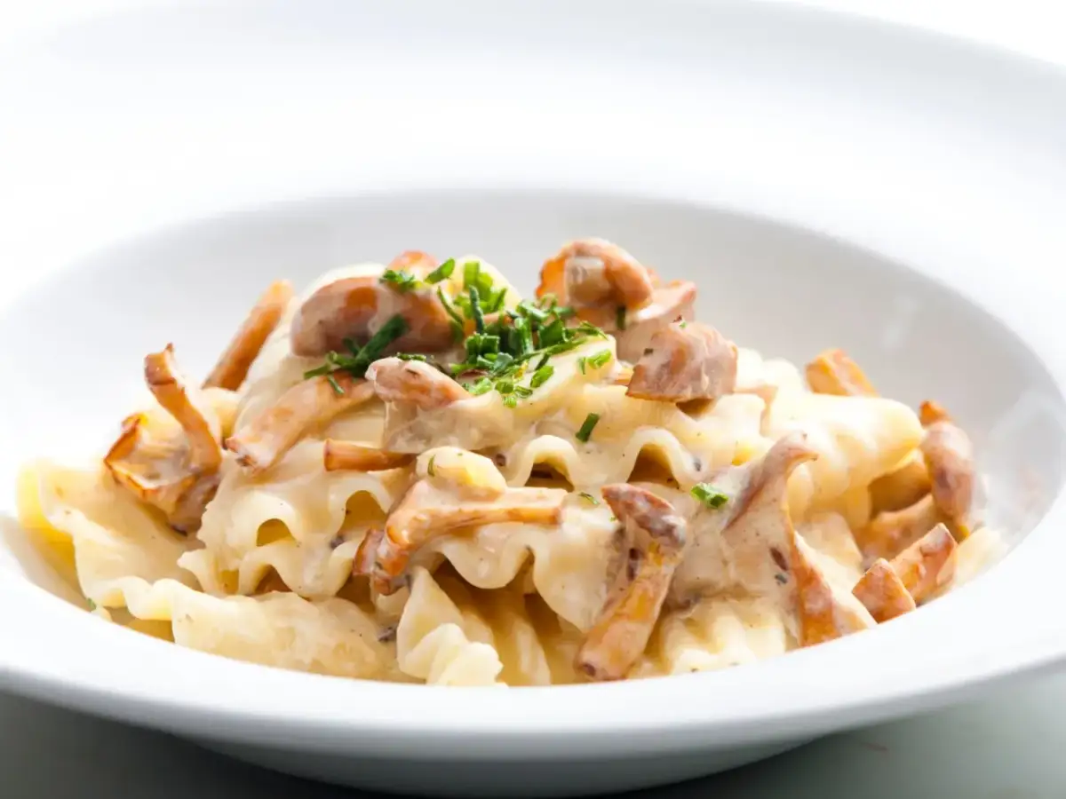 Pyszny makaron z kurkami w kremowym sosie, posypany świeżą natką pietruszki. Idealne danie dla miłośników grzybów.