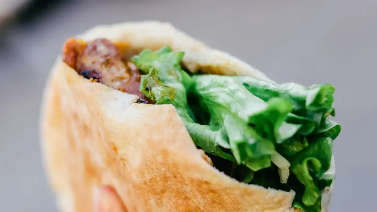 Kebab w bułce z mięsem i świeżą sałatą.