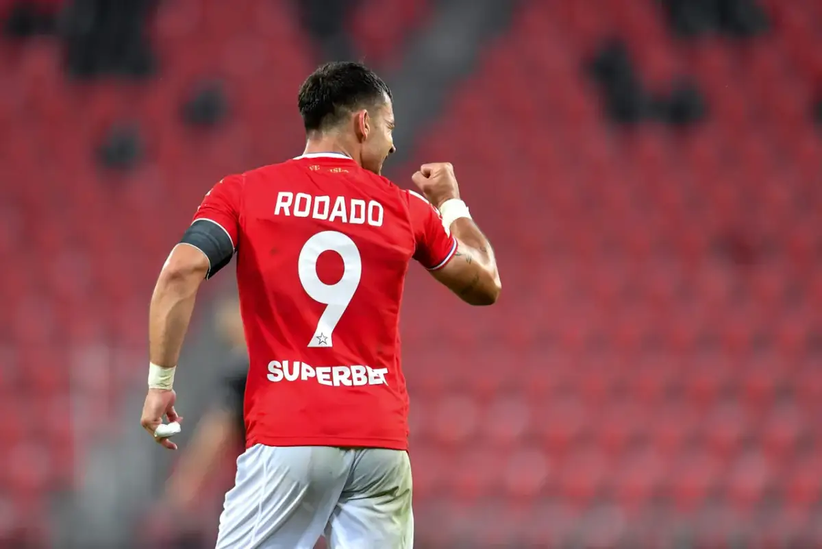 Piłkarz Rodado z numerem 9 świętuje bramkę. Jego koszulka z napisem SUPERBET i logo I Ligi Statystyki świadczy o jego sukcesach.
