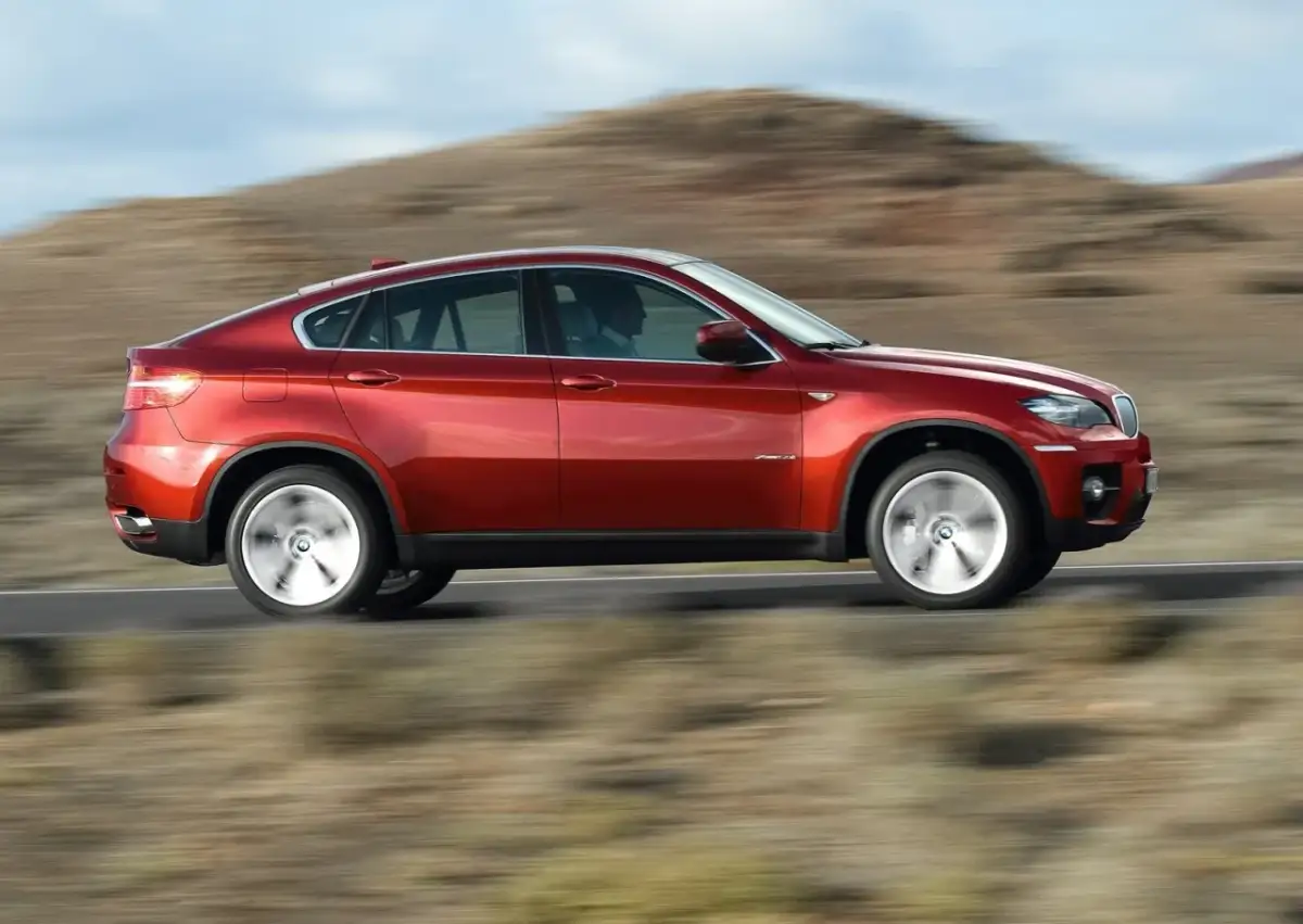 Czerwony BMW X6 pędzi po pustynnej drodze. Oto moto!
