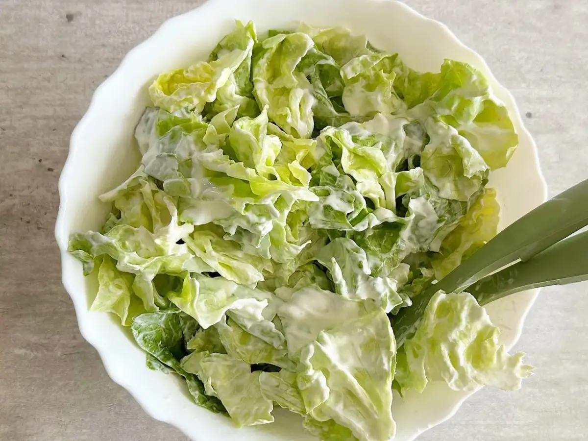 Chrupiąca sałata ze śmietaną, podana w białej misce. Idealna na lekki posiłek.