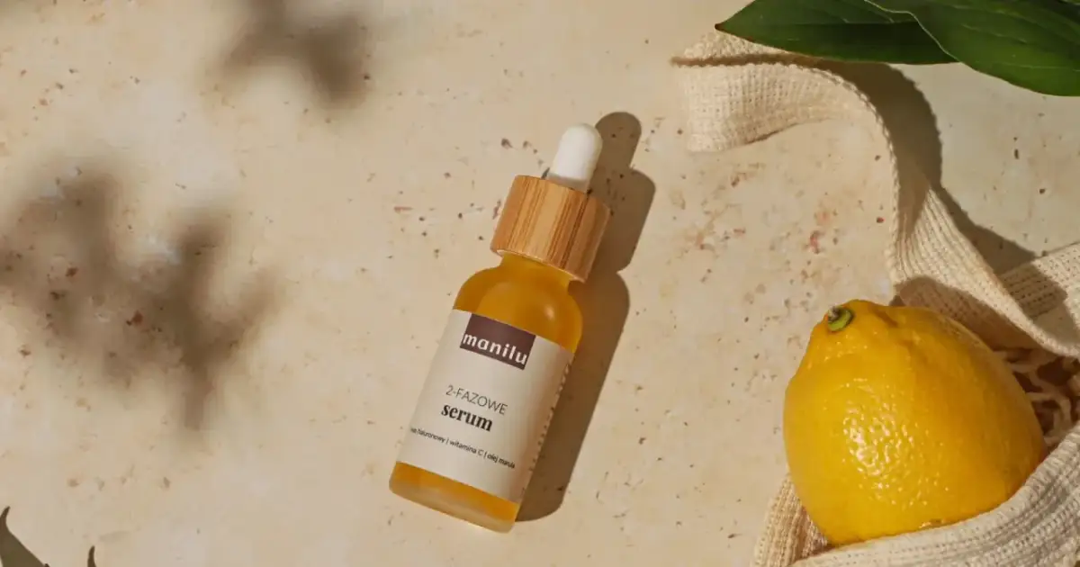 Szukasz idealne serum do twarzy po 50.? Na zdjęciu dwufazowe serum z kwasem hialuronowym, witaminą C i olejem marula, obok cytryny i liści.
