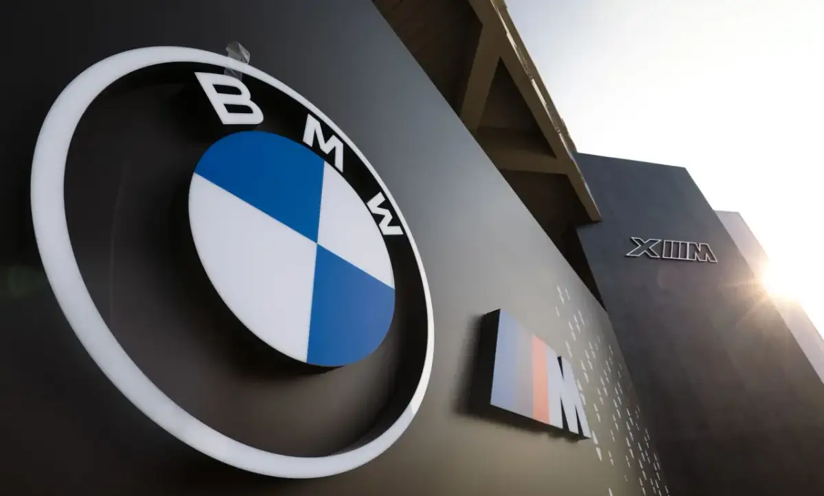 Logo BMW i oznaczenie M, symbole niemieckich marek samochodów, na ciemnej ścianie budynku.