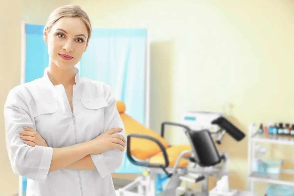 Lekarka w białym fartuchu w gabinecie ginekologicznym. Dowiedz się, jak zapisać się do ginekologa na NFZ.