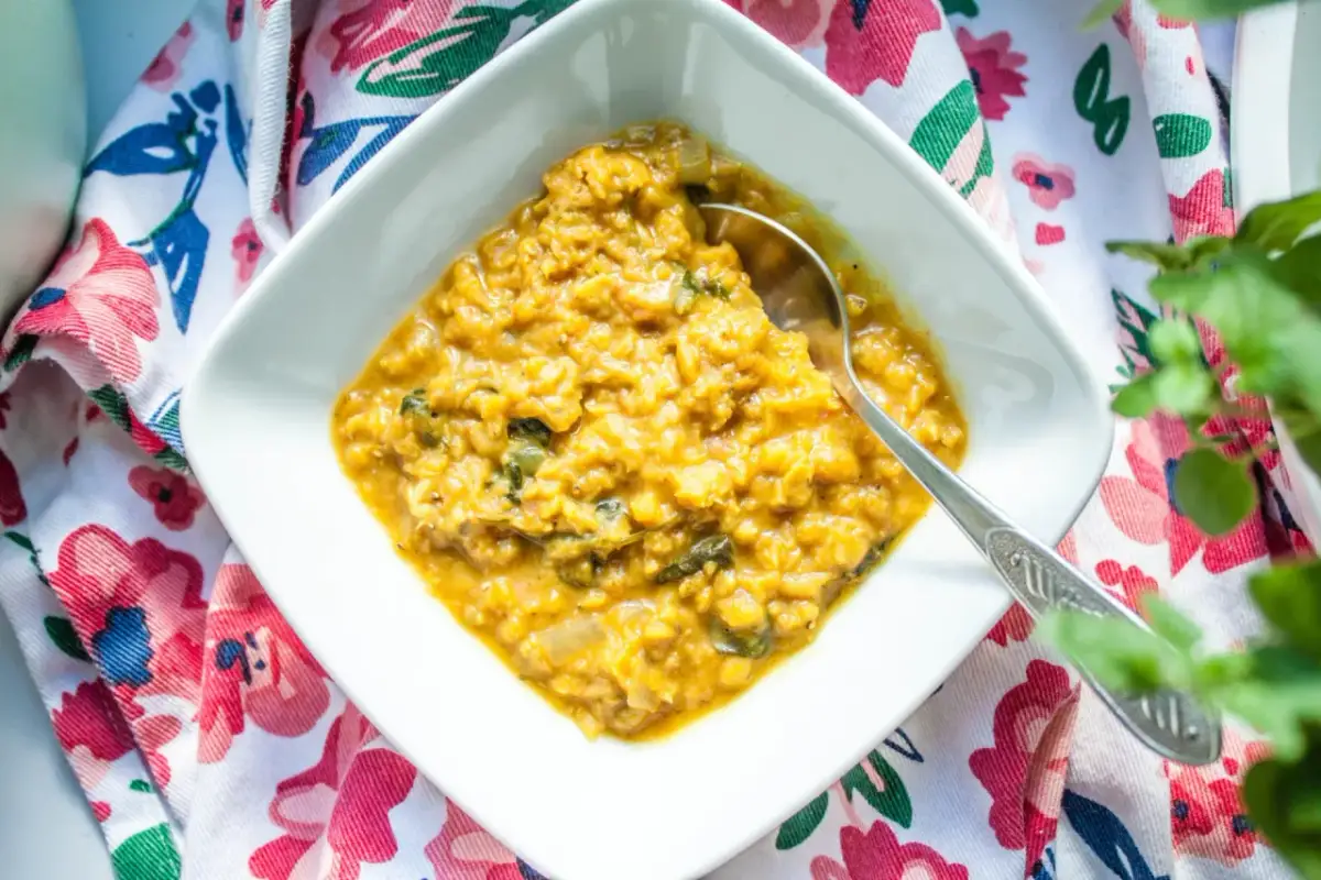 Miseczka z żółtym curry i łyżką na kwiecistym tle.