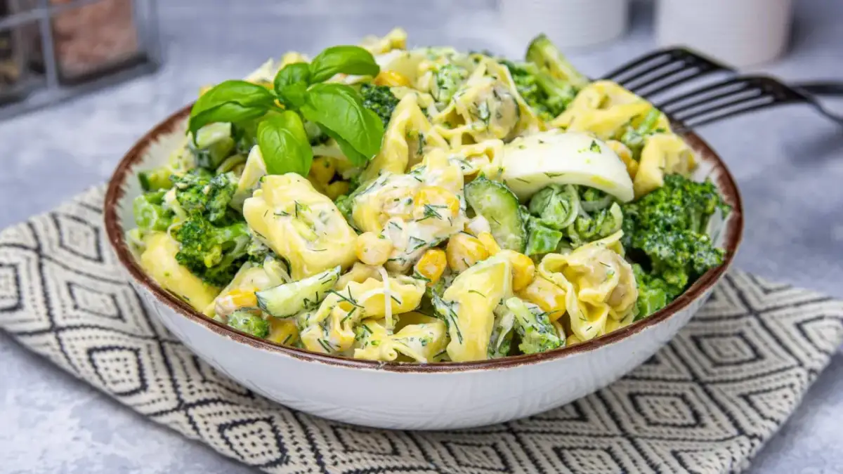 Pyszna sałatka z makaronem tortellini, brokułem, jajkiem, kukurydzą, ogórkiem i słonecznikiem, polana kremowym sosem.