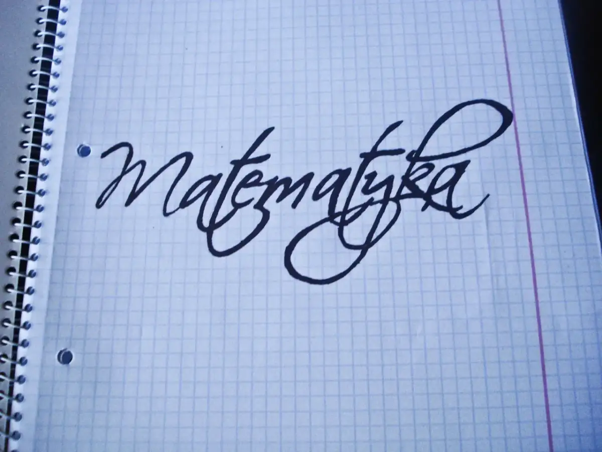 Napis "Matematyka" wykonany ozdobnym pismem odręcznym na kartce w kratkę.