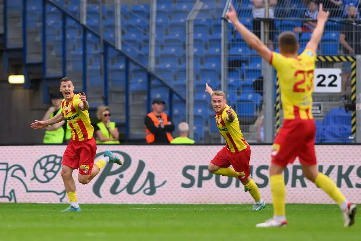 Piłkarze w żółto-czerwonych strojach świętują na boisku.