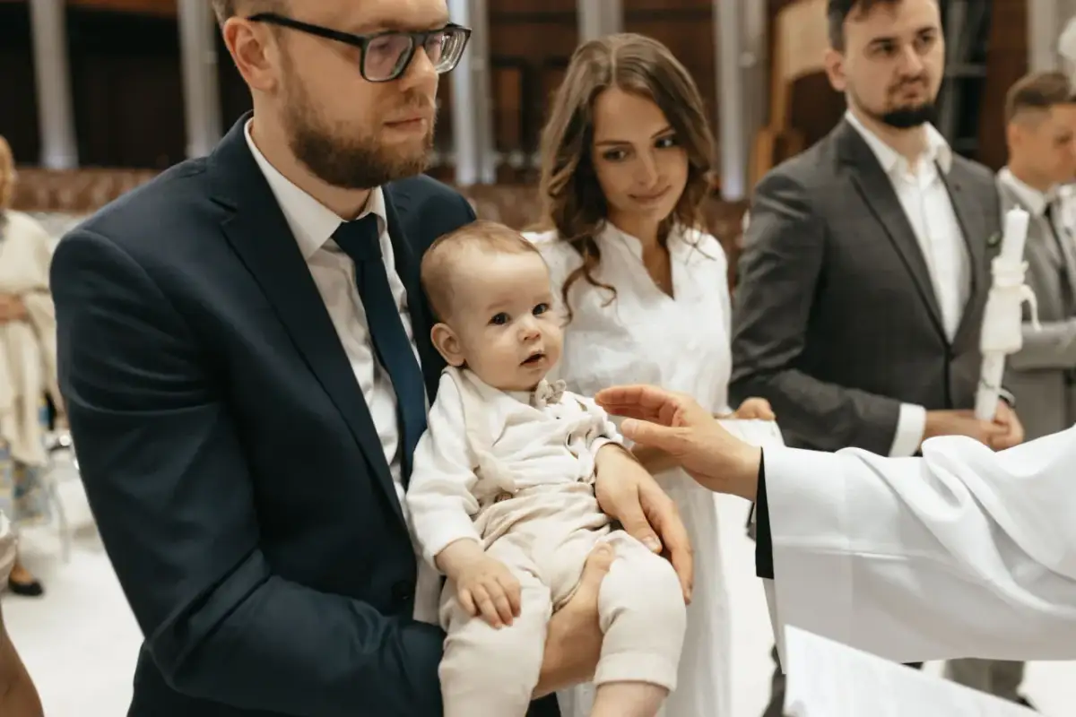 Rodzice z dzieckiem podczas chrztu. Zastanawiasz się, ile bierze fotograf za chrzciny? Warto mieć pamiątkę.